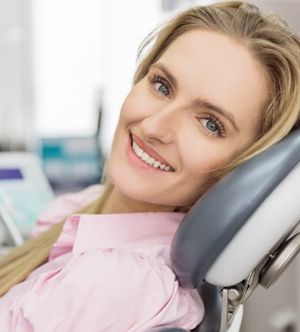Woman smiling in dental chair wearing pink shirt at dentist office