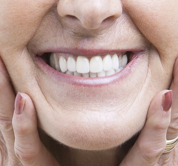 Close-up of person's smile showing white, healthy teeth and gums during dental examination.