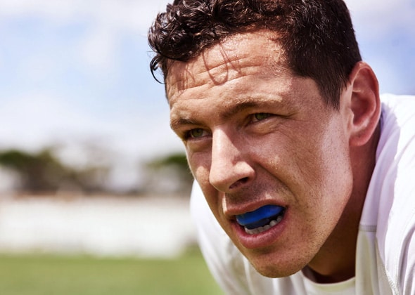 Man with blue mouthguard outdoors on sports field during daytime
