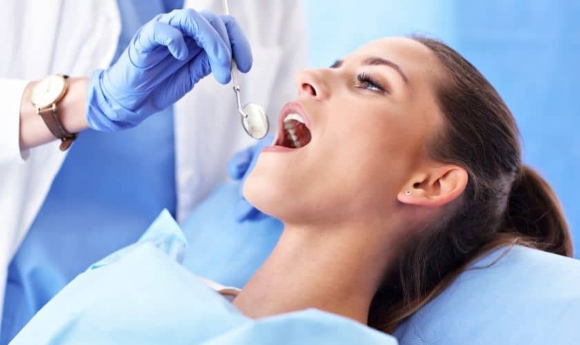 Patient receiving dental treatment with dentist in blue gloves during examination at Saginaw dental practice.