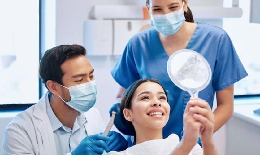 Dentist and dental hygienists showing female patient her bright smile in mirror at Saginaw dental office.