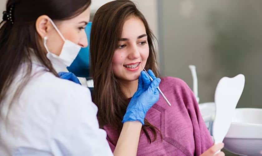 Dentist in blue gloves showing digital results to smiling patient during consultation.